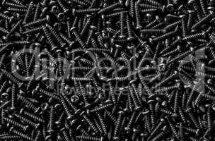Background pile of shiny black screws