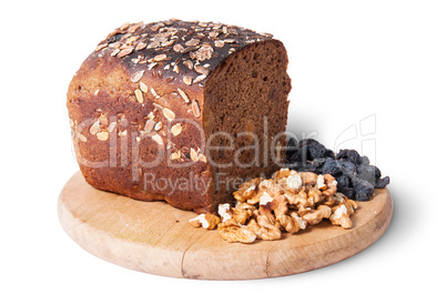 Bread with seeds on wooden board with raisins and nuts