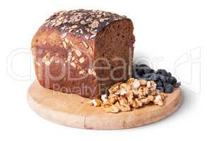 Bread with seeds on wooden board with raisins and nuts
