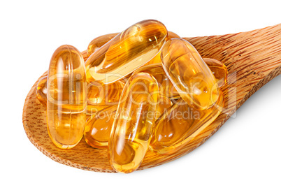 Cod liver oil omega 3 capsules on wooden spoon