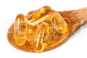 Cod liver oil omega 3 capsules on wooden spoon