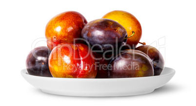 In front mix of red and violet plums on white plate