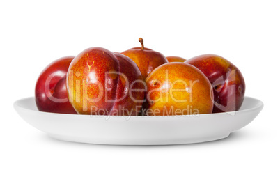 In front red and yellow plums on white plate