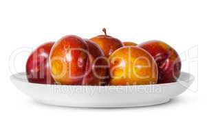 In front red and yellow plums on white plate