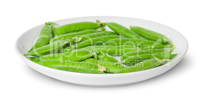 In front several pods of peas on a white plate