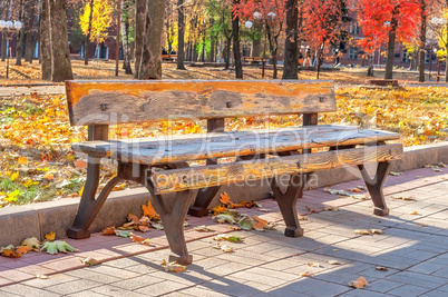 Lonely old bench in autumn city park on a sunny day