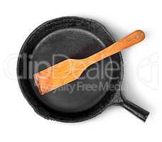 Old cast iron pan with wooden spatula top view