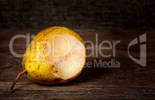 One bitten pear lying on a wooden table
