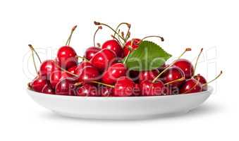 Pile of sweet cherries with leaf on white plate