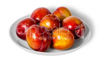 Red and yellow plums on white plate