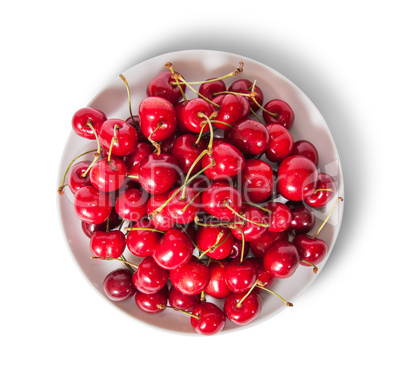 Red sweet cherries in white plate top view