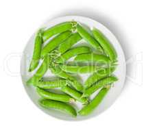 Several pods of peas on a white plate top view