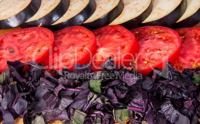 Sliced eggplant tomato and basil leaves horizontally