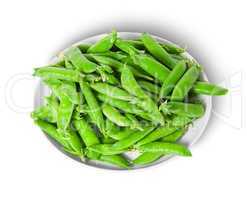 Small pile of green peas in pods on white plate