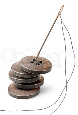 Stack of old buttons and needle with thread