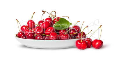 Sweet cherries with leaf on white plate and three near