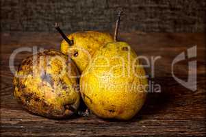 Three old pears on a wooden table