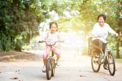 Grandmother and granddaughter biking outdoor.