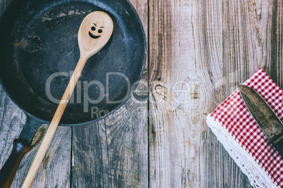 black frying pan with a wooden spoon on a gray table
