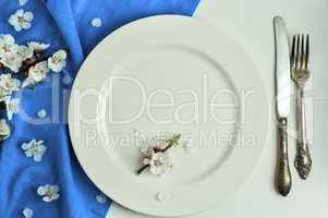 White plate and cutlery, near a cherry blossom branch