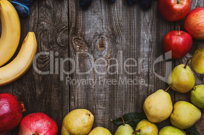 Fresh fruits on a gray wooden surface, bananas, apples, plums an
