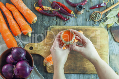 Women's hands hold a jar of carrot juice