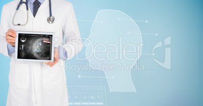 Digitally generated image of male doctor showing digital tablet with human face graphics in backgrou