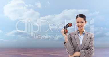 Portrait of businesswoman holding binoculars while standing against sky
