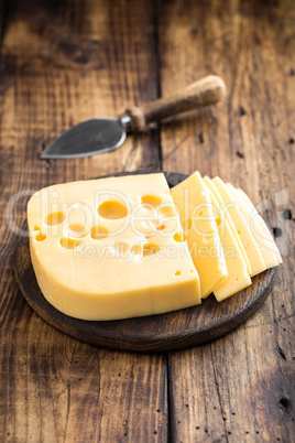 Delicious Swiss yellow cheese on dark wooden rustic background closeup