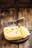 Delicious Swiss yellow cheese on dark wooden rustic background closeup