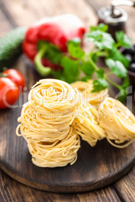 Raw all'uovo pasta, egg noodles with cooking ingredients on dark wooden rustic background, traditional italian cuisine