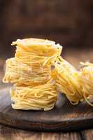 Raw all'uovo pasta, egg noodles on dark wooden rustic background, traditional italian cuisine