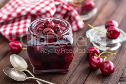 Berries cherry with syrup in a glass jar. Canned fruit