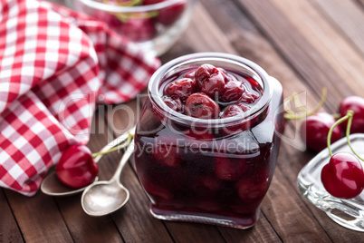 Berries cherry with syrup in a glass jar. Canned fruit