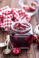 Berries cherry with syrup in a glass jar. Canned fruit