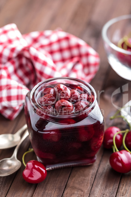 Berries cherry with syrup in a glass jar. Canned fruit