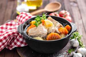 Meat stewed with carrots and potatoes in sauce on wooden rustic background