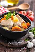 Meat stewed with carrots and potatoes in sauce on wooden rustic background