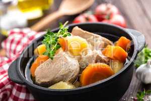 Meat stewed with carrots and potatoes in sauce on wooden rustic background