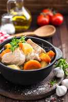 Meat stewed with carrots and potatoes in sauce on wooden rustic background