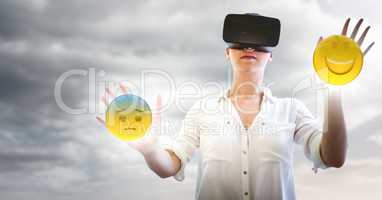 Woman in VR with network and emojis with flares against cloudy sky