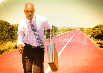 Business man running with briefcase on track in desert with flare