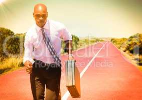 Business man running with briefcase on track in desert with flare