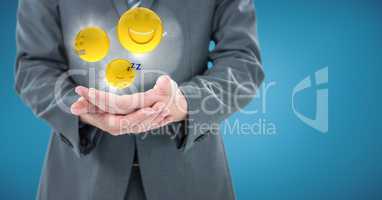 Business man mid section with hands together and emojis with flares against blue background