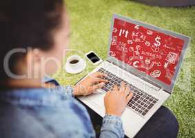 Woman on grass with laptop showing white business doodles and red background