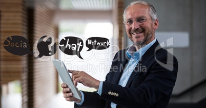 Happy businessman using tablet PC with chat signs flying in office