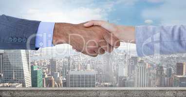 Digitally generated image of  businesswomen doing handshake with city in background