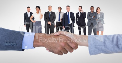 Cropped image of business people doing handshake with employees in background