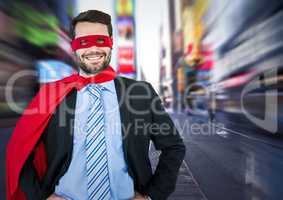 Business man superhero with hands on hips against blurry street