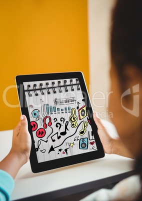 Kid at desk holding tablet showing music doodles on sketchbook
